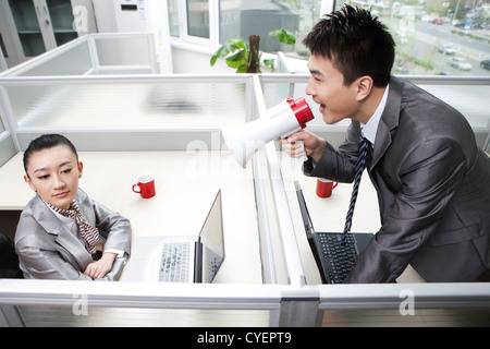 Businessman shouting to a businesswoman using megaphone Stock Photo