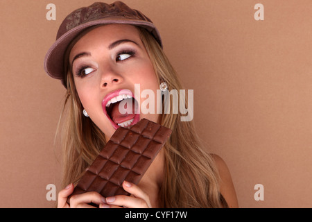 Laughing beautiful woman holding a slab of unwrapped chocolate close to her face. Stock Photo