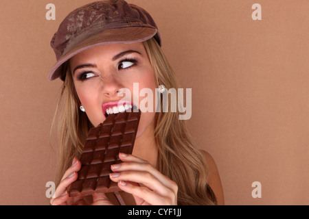 Laughing beautiful woman holding a slab of unwrapped chocolate close to her face. Stock Photo