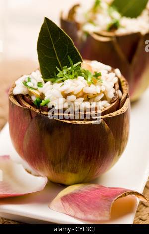 Stuffed artichokes with risotto on elegant table with golden fork Stock Photo