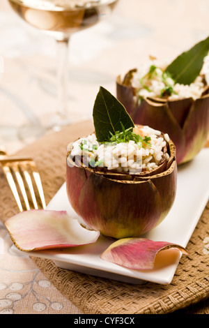 Stuffed artichokes with risotto on elegant table with golden fork Stock Photo