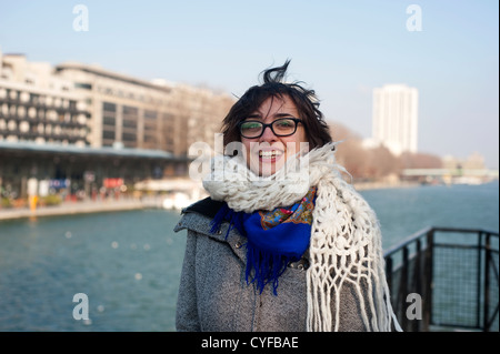 Paris, France - Young woman wearing coat and scarf on a  winter sunny day, in front of  Canal Stock Photo