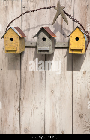 Three rustic birdhouses hanging on a wooden fence. Stock Photo