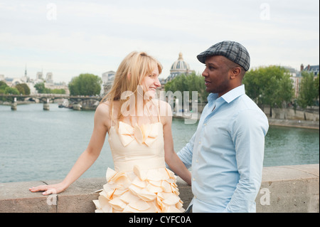 Paris, France - Mixed race couple looking at each other standing on a bridge on the Seine River Stock Photo