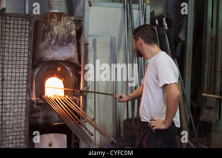 Worker in a glass factory in Murano in Venice heating glass in a furnace Stock Photo