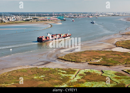 The Netherlands, Nieuw Namen, Container boat in Westerschelde river. Industrial area of Antwerp ( Belgium ) and tidal marshland. Stock Photo