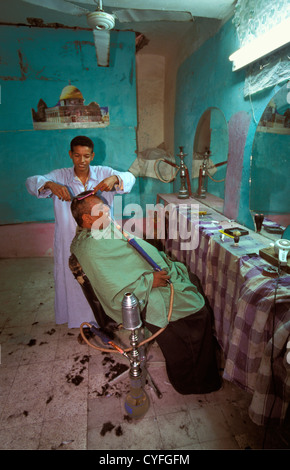 Egypt, Nile river, Luxor, West Bank, hair dresser and client smoking water pipe Stock Photo