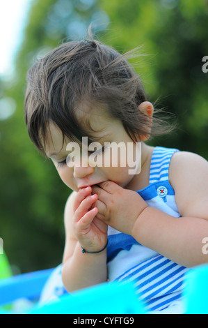 10 month old baby eating a strawberry outdoors in England. Stock Photo