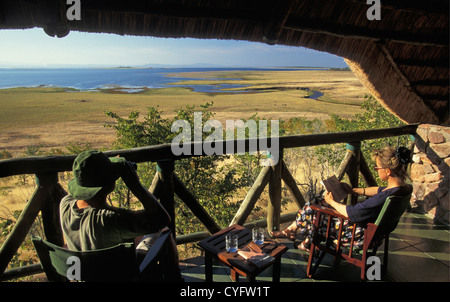 Zimbabwe, near Kariba, Lake Kariba, Katete Safari Lodge, Tourists, Woman reading and man with binoculars Stock Photo