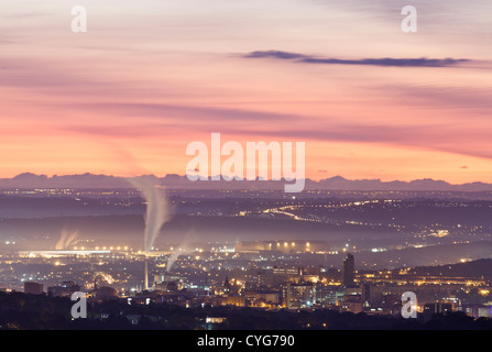 Industrial cityscape in the predawn light as the sun glows on the horizon Stock Photo