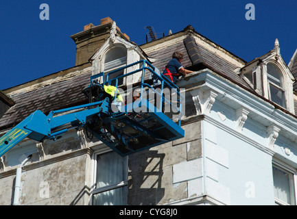 Workmen using a cherry picker to repair gutters on property in the U.K. Stock Photo