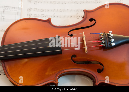 A close up of the body of a violin resting on some printed sheet music. Stock Photo