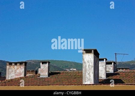 Chimneys on roof with blue sky and hills Stock Photo