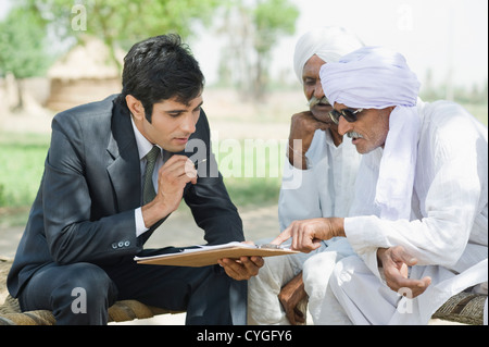 Financial advisor explaining to farmers about agriculture loan Stock Photo