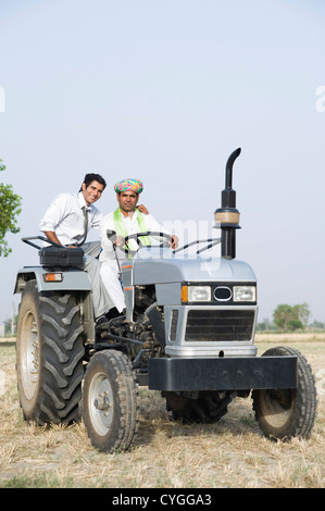 Financial advisor sitting on a tractor with a farmer Stock Photo