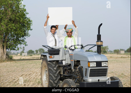 Financial advisor and a farmer showing a placard on a tractor Stock Photo