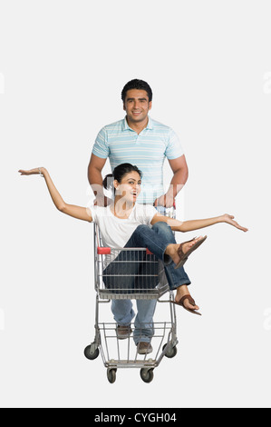Man pushing a woman sitting in shopping cart Stock Photo