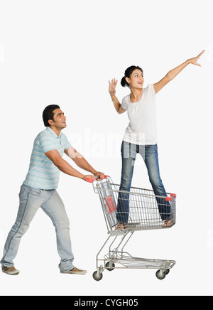 Man pushing a woman standing in a shopping cart Stock Photo