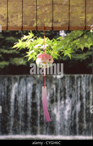 Wind chime and green maple leaves with waterfall in the background Stock Photo