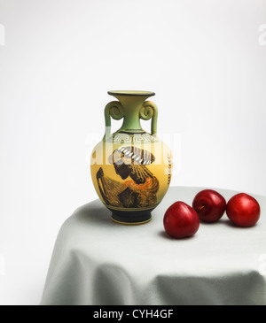 Greek Vase and red Plums on round Table Stock Photo