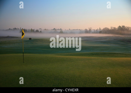 Golf flag on Green in early morning mist and fog Stock Photo