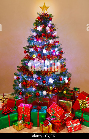 Photo of a decorated Christmas tree lit up with fairy lights and surrounded by gift wrapped presents, Santa has been! Stock Photo