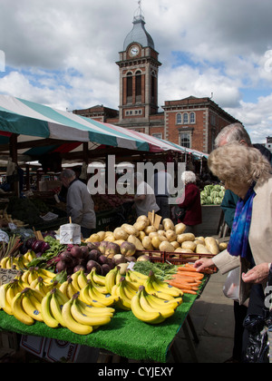 Man and woman looking on fruit and veg stall on outdoor market Chesterfield town in Derbyshire England Stock Photo