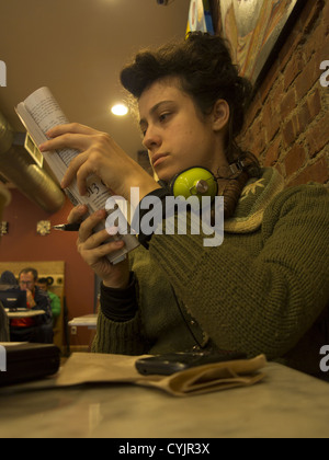 Young woman reads and studies in a cafe in Brooklyn, NY. Stock Photo
