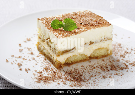 Tiramisu - Classical Dessert with Coffee on white plate. Garnished with Mint. Stock Photo