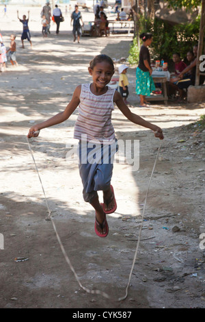 Indonesia, Papua New Guinea, Tubuserea Village. Young Motuan girl playing jump rope in street. Stock Photo