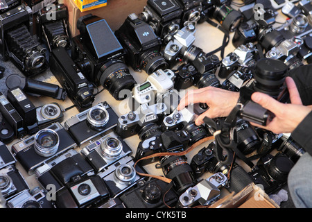 Shopper examines chooses, second hand pre-owned analogue film Camera El rastro street market, Madrid, Spain Stock Photo