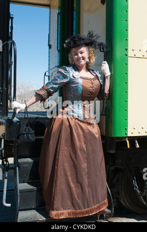 USA, Nevada. Woman in period dress beside an old steam locomotive at historic Gold Hill train station Virginia CIty, Nevada. Stock Photo