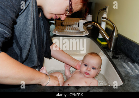 A six month old baby boy being bathed in the kitchen sink Stock Photo