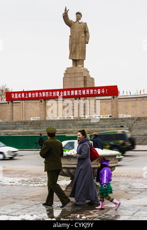 Soldier´s Chinese family walking by the huge statue of Mao Zedong in Kashgar, Xinjiang, China Stock Photo