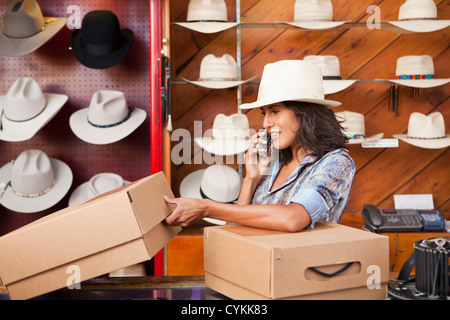Ecuadorian woman talking on cell phone in hat store Stock Photo