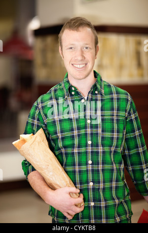 Man carrying baguette in grocery store