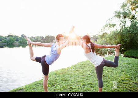 Couple practicing yoga by water Stock Photo