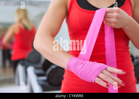 Boxer wrapping her hands in gym Stock Photo