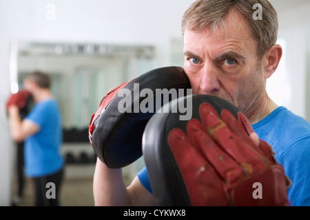 Trainer wearing padded gloves in gym Stock Photo