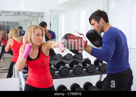 Boxer practicing with trainer in gym Stock Photo