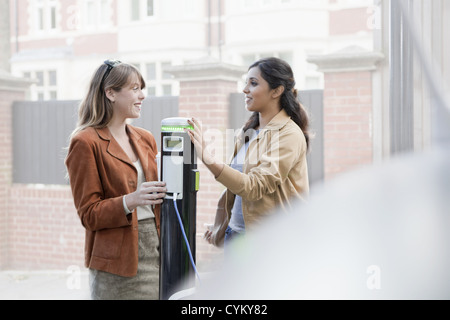 Women charging electric car on street Stock Photo