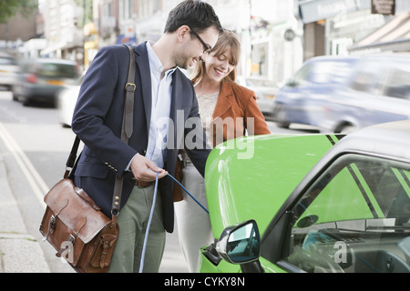 Couple charging electric car on street Stock Photo