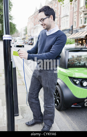 Man charging electric car on street Stock Photo
