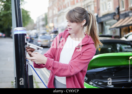 Woman charging electric car on street Stock Photo