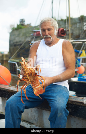 Fisherman holding lobster on boat Stock Photo