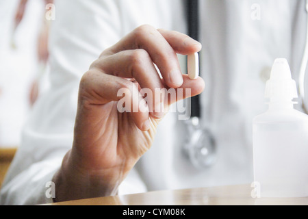 Doctor holding pill in office Stock Photo