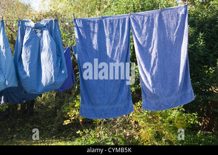 Blue clothing hanging from washing line drying in autumn sunshine Stock Photo