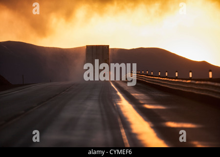 Truck driving down road on wet highway Stock Photo