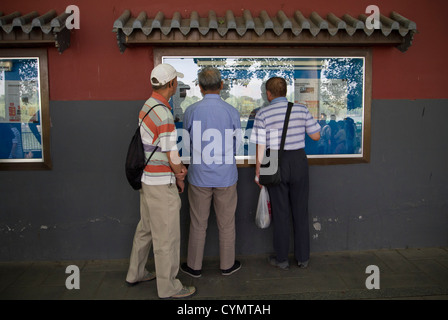 Three men reading newspapers on display in Beihai Park, Beijing, China Stock Photo