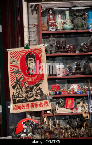 A poster of Chairman Mao on sale in a shop alongside religious figures and icons in Liulichang Street, Beijing, China. Stock Photo